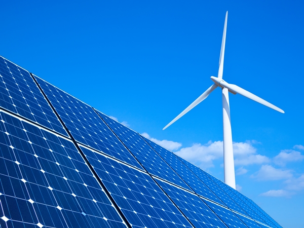 Solar panels and wind turbine against blue sky