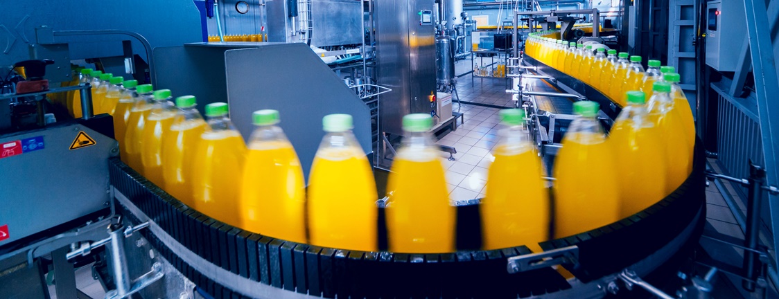 longview of bottled juices moving on a conveyor belt with machinery in the background
